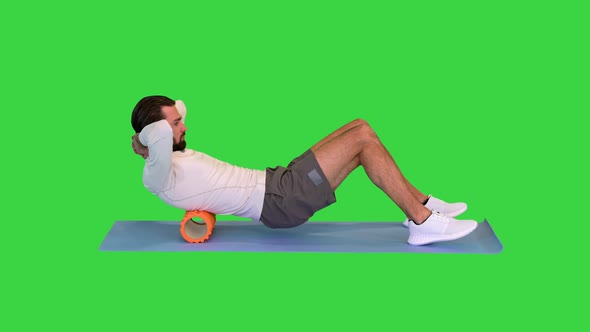 Athlete Massaging Upper Back Muscles with Foam Roller on a Green Screen Chroma Key