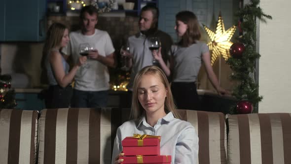 beautiful girl in room decorated garlands opens box with Christmas gift. alt