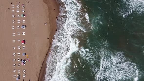 aerial view of waves and empty lounge in the morning. empty beach and deck chairs.