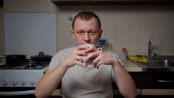 Man Drinking Tea in the Evening While Sitting in the Kitchen at the Table, Camera Movement alt