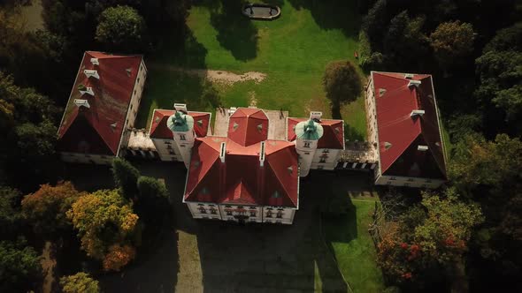 AERIAL front view of Castle. Flight over beautiful castle, located in landscape park with green tree alt