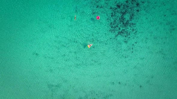 High aerial view of two young girls swimming and playing in sea with inflatables. alt