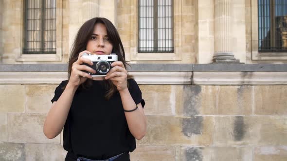 Pretty Woman Making Photo Rewinding a Film Camera on Background