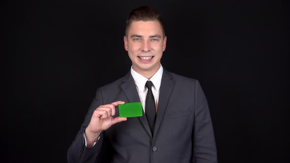 Young Businessman Presents a Bank Green Card and Shows Like with His Hand. Chromakey Green Card alt