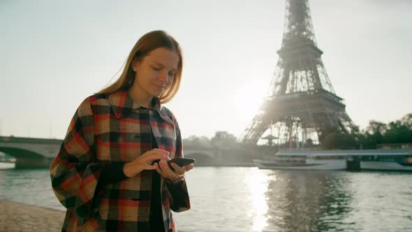 Young Female Tourist Uses Smartphone App Near Eiffel Tower in Paris France