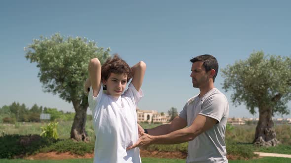 A Young Guy is Outside Exercising with a Personal Trainer