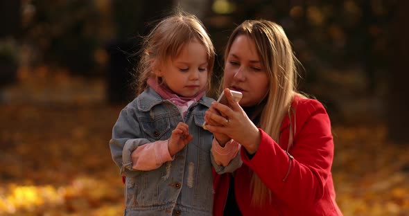 Mother and Daughter Using Smartphone in Park