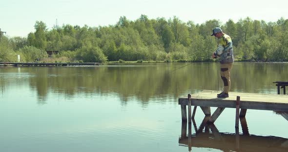 Man Fishing on Wooden Pier Near Lake