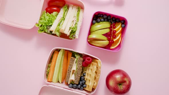 Shot of School Lunchboxes with Various Healthy Nutritious Meals on Pink Background