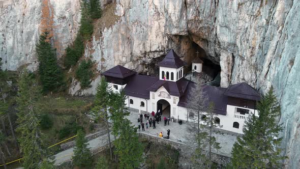 Aerial drone view of The Ialomitei Cave in Romania. Entrance into the cave with tourists in Bucegi M alt