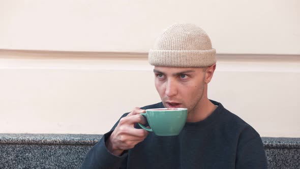 A Closeup Portrait of an Attractive Young Caucasian Man Holding Coffe Cup at Cafe alt