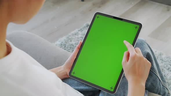 Woman holding in hands a digital tablet with green screen for internet online. alt
