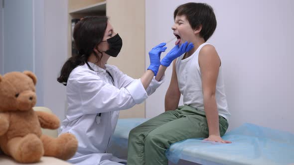 Side View Female Pediatrician Checking Little Patient Sore Throat with Disposable Spatula alt