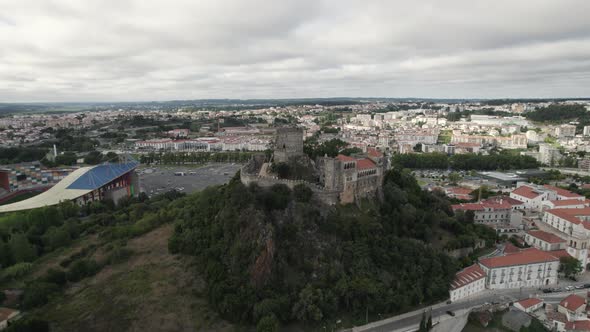 Majestic Leiria Castle perched on hilltop overlooking city; drone pan