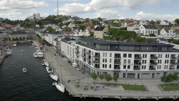 Boats Moored At The Pollen Harbour With The Grand Garden Building In Langbryggen, Arendal, Norway. alt
