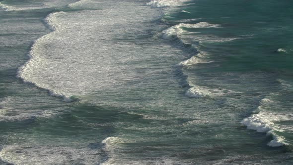 Waves crashing to shore, creating seafoam as it folds