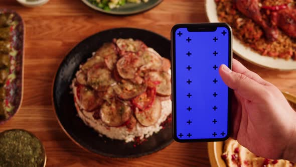 Maqluba Hummus Dolma Kabsa Tabbouleh Closeup Smartphone with Blue Chroma Key Screen Middle Eastern alt