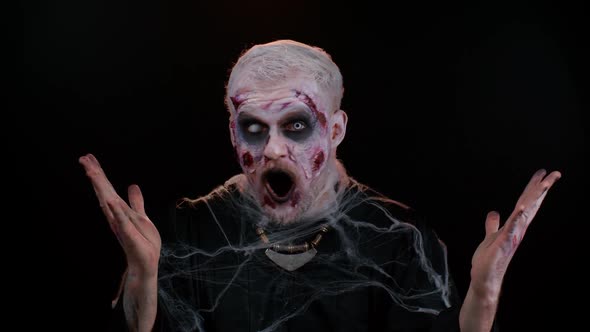 Frightening Man Halloween Zombie Raising Hands in Surprise Looking Shocked By Sudden Victory alt