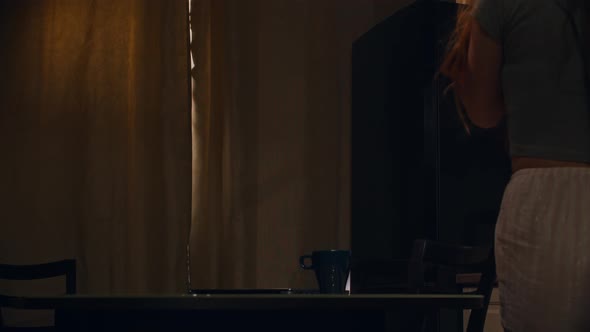 Early Morning  Young Woman Opens Up the Curtains on the Kitchen alt