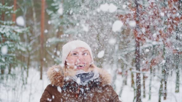 Winter Fun Outside Woman Throwing Snow in the Air and Smiling alt