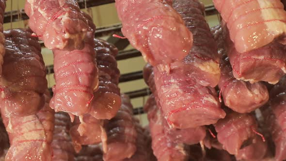 Pieces of Raw Meat Tied with Food Thread, Which Are Prepared for Baking in Industrial Ovens alt