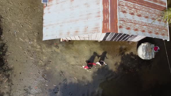 Aerial top down shot showing woman and daughter leaving flooded homestead in Cambodia. alt