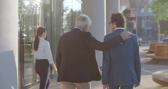 Follow Shot of Businessmen Partners Dressed in Formal Suit Walking and Talking Outside Job Center alt