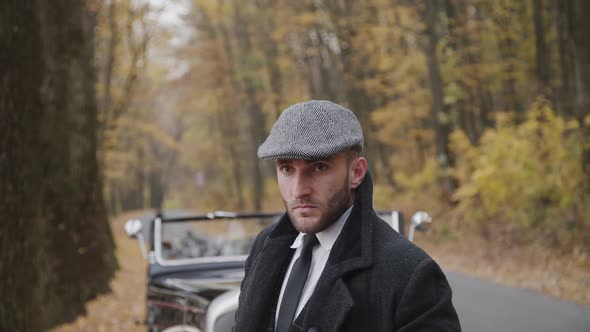 Portrait of Handsome Serious Gentleman in Autumn Park at Retro Car alt