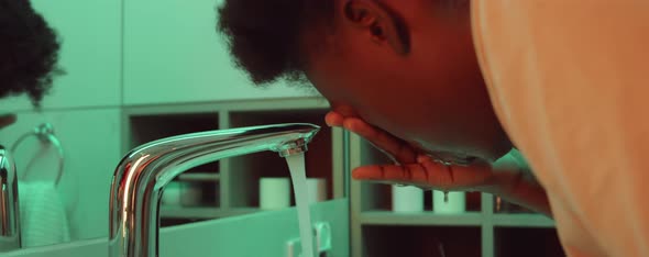 African American Woman Washing Face in Bathroom alt
