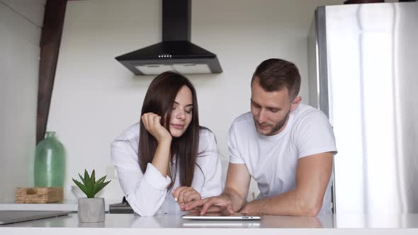 Young couple looking at products in an online store on their tablet alt