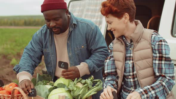 Multiethnic Farmers Putting Price Tags on Vegetables for Sale alt