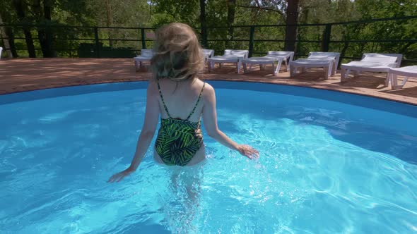 Slim Blonde Woman in Fashion Swimsuit Is Entering in Pool and Flirting with Camera