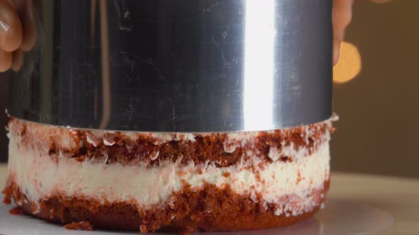 Hands Removes a Metal Mold From a Red Velvet Cake alt