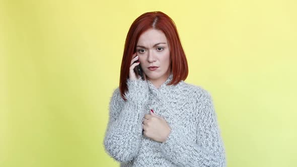 Emotionally Red Haired Woman Wearing Cozy Gray Sweater Talking at Call Phone.