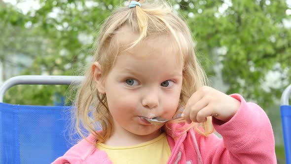 Cute Little Girl Sits And Eats Ice Cream. Child With Ice Cream.  Funny Little Girl With Ice Cream.  alt