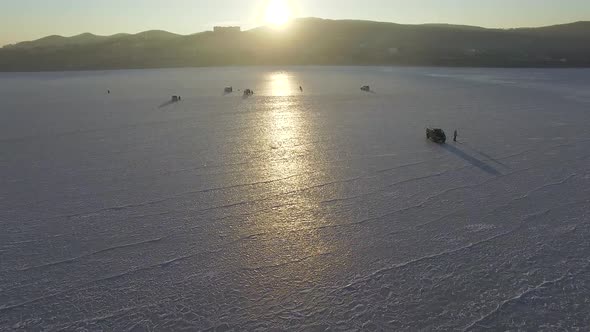 Winter Frozen Sea Captured From a Drone Fishermen Sit on Ice and Fishing alt