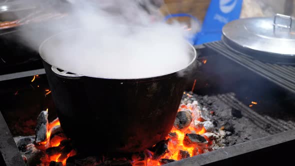Big Vat of Hot Food Is Cooked on the Coals on a Street Christmas Market alt