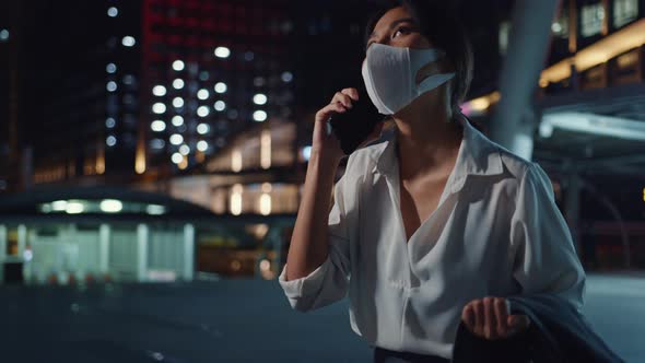 Asia businesswoman wear medical face mask talk via phone while walk alone outdoor.