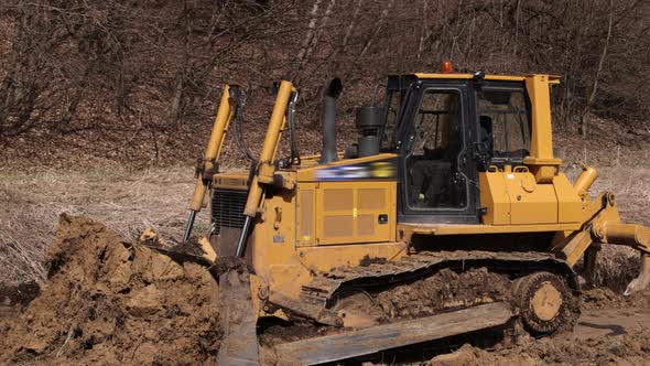 Bulldozer at Construction Site Shovels Soil Into a Heap alt