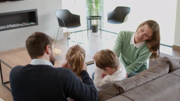 Happy family with two kids enjoy time together on couch in living room