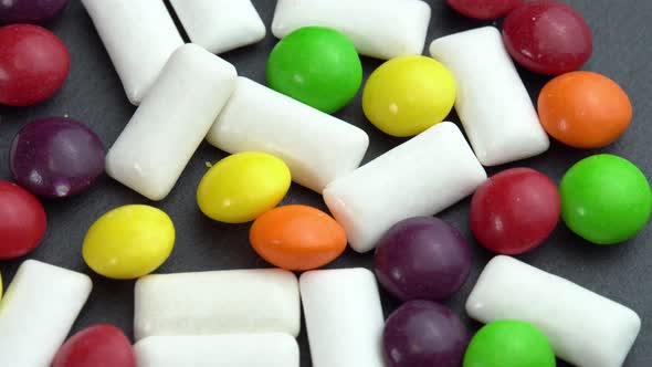 Sweets Colored Candies Skittles and Mint Chewing Pads Colored Sweets Rotate on a Black Plate alt