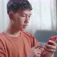 Close Up Of Asian Boy Footwear Designer Looking At Smartphone While Working On A Laptop At Home - VideoHive Item for Sale