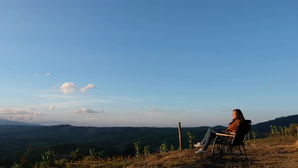 A female traveler sitting and watching sunrise on mountain peak in the morning