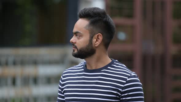 Profile View of Young Bearded Indian Man Waiting and Thinking Outdoors