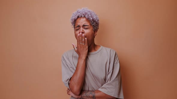 Tired African American Woman Yawns Closing Eyes and Covering Mouth with Hand alt
