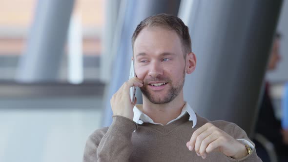 Young businessman using cell phone in office lobby