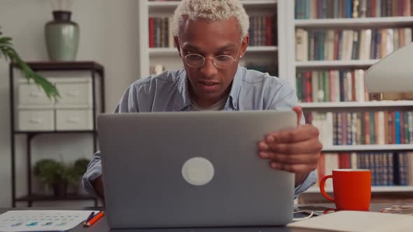 Confident African Man Using Laptop Sitting at His Home Desk alt