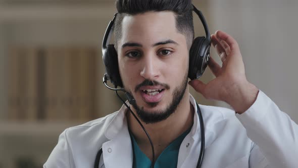 Web Camera View Young Male Hispanic Doctor Practitioner Arab Man Wear Headphones with Microphone alt