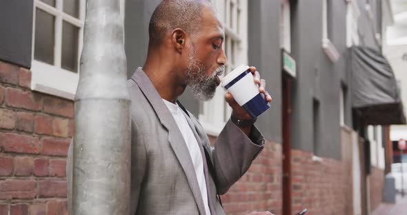 African American man drinking a coffee and using his phone alt