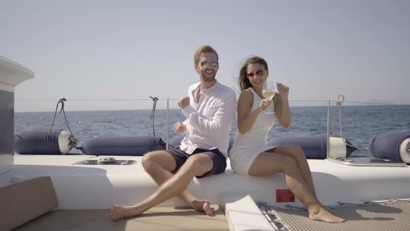 Rich Young Couple Dancing on Yacht Seated alt